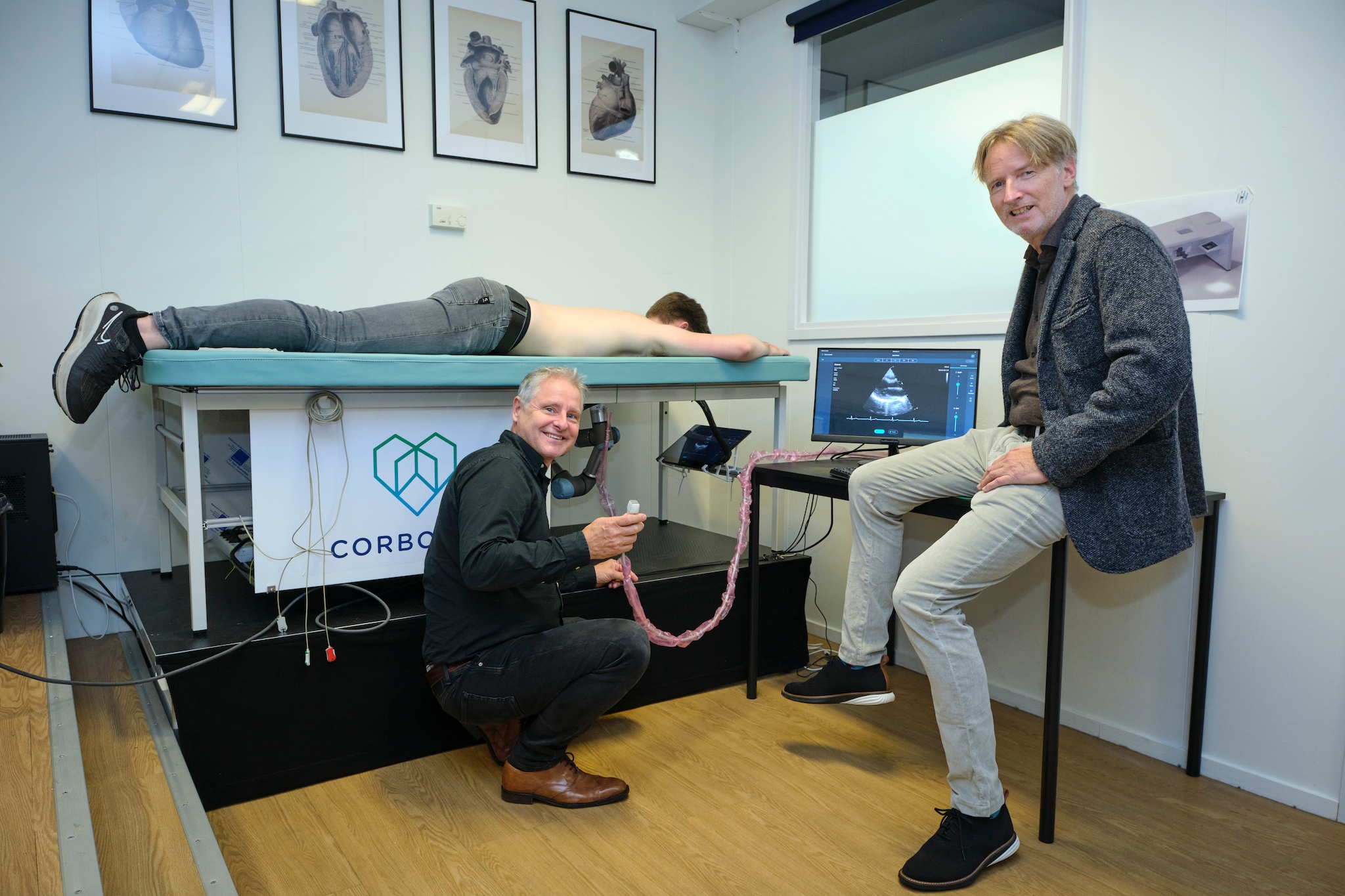 Eelko Ronner (links) demonstreert samen met Adriaan van Donk de  echorobot. Software enigneer Rembrandt Klazinga speelt voor model en ligt op de tafel zoals patiënten straks ook doen. Fred Libochant / DCI Media West