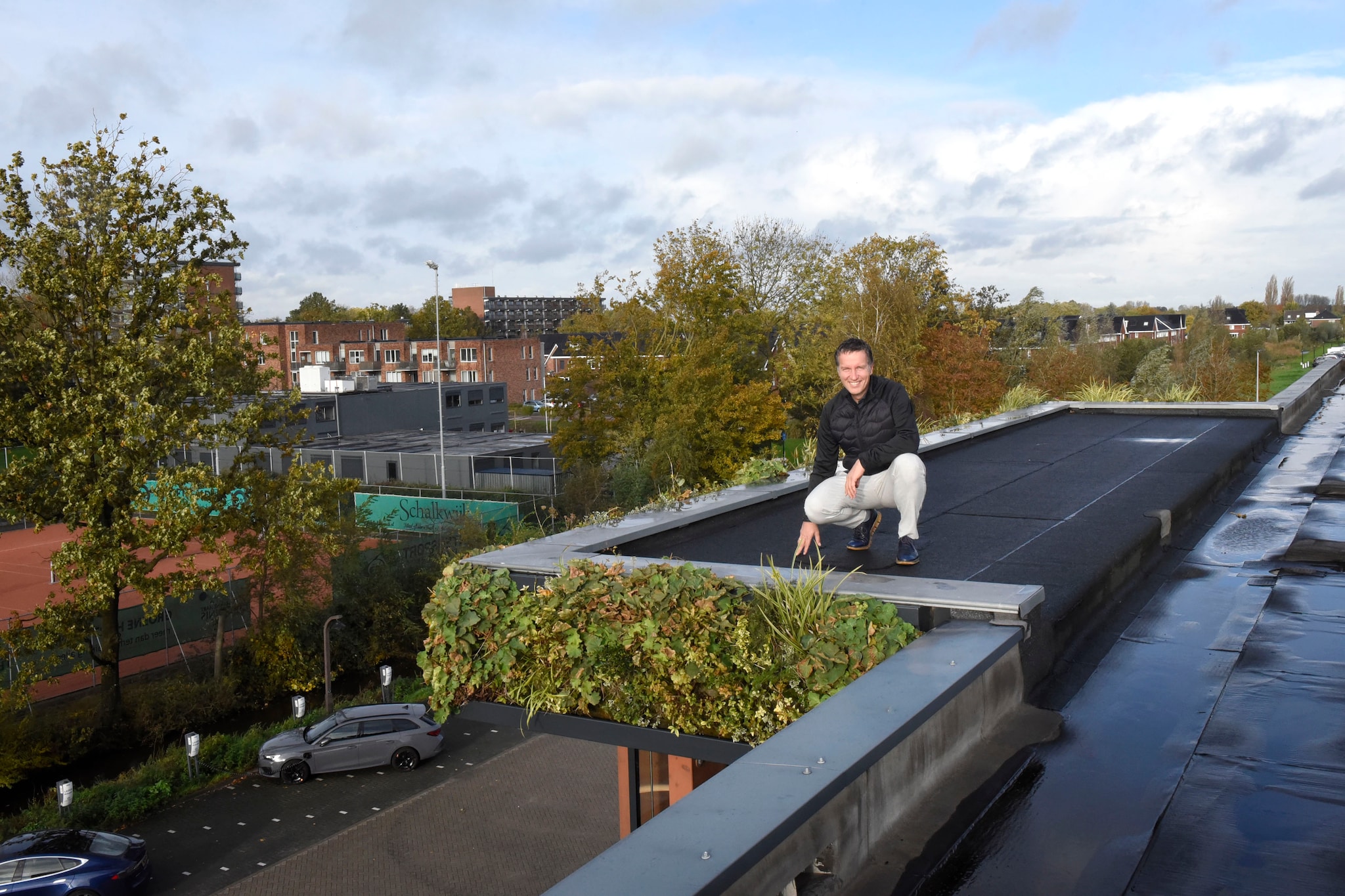 Marien Groenendijk op het dak van zijn bedrijf Groenendijk Bedrijfskleding. Met op de achtergrond de wijk in Woerden, die hij wil gaan voorzien van stroom door middel van elektrische laadpalen. Rianne den Balvert