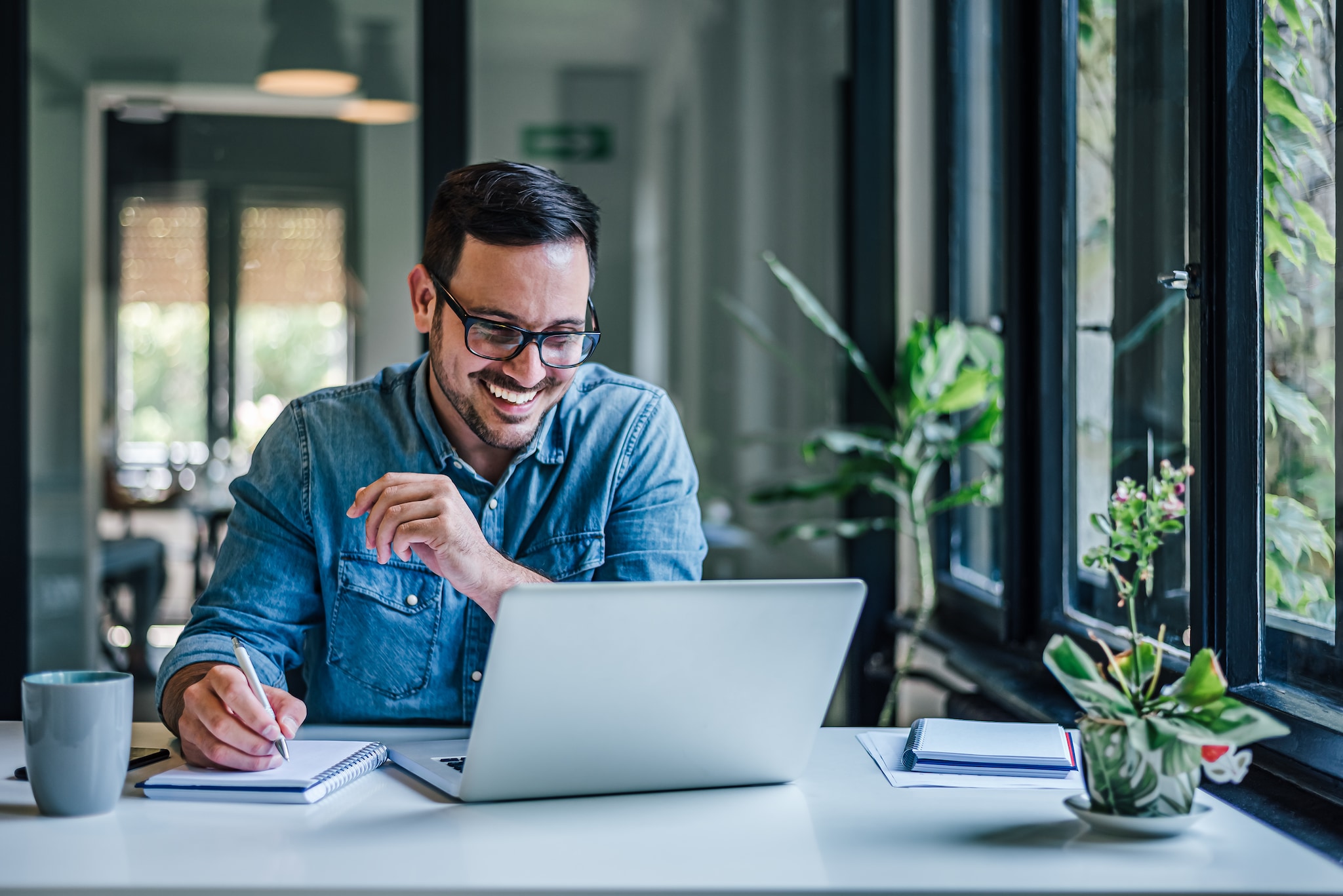 Cheerful adult man with glasses, taking notes on the conference call. Getty Images/iStockphoto