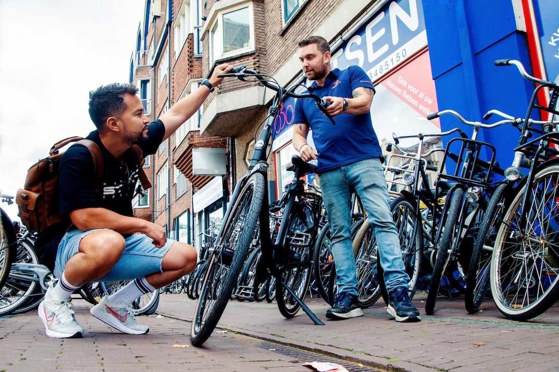 Eigenaar Jip Eichelsheim (rechts) tijdens de verkoop van een fiets aan de Columbiaanse student Gerson. Beeld: Ruud Voest