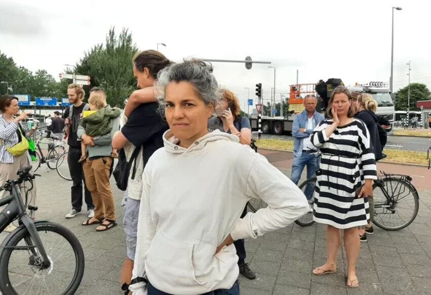 Liv Kooijmans van houtbedrijf Buurman kijkt vanaf het Marconiplein verslagen toen hoe de onderneming - net als vele andere bedrijven - in rook is opgegaan. Foto: AD