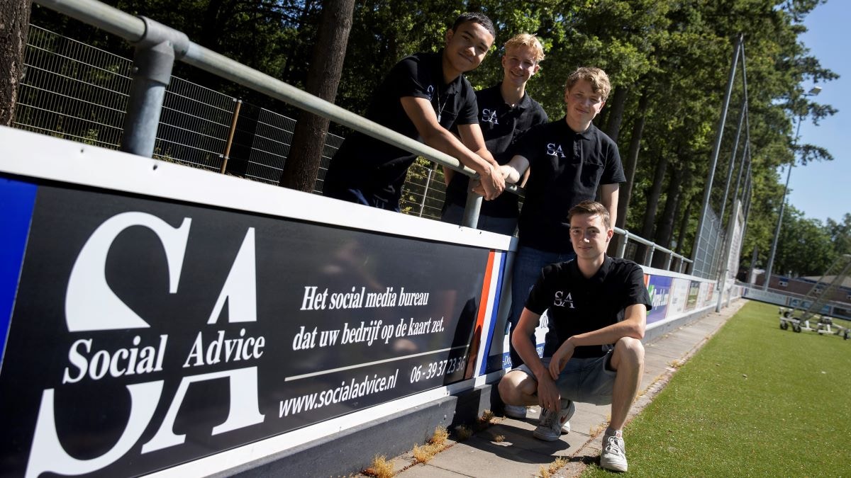 Jimmy Clement, Sem Dekker, Stijn Kuipers en Jasper van Gestel (vanaf links) van jeugdonderneming Social Advice bij hun reclamebord op het sportpark van Stiphout Vooruit. Foto: Kees Martens/DCI Media