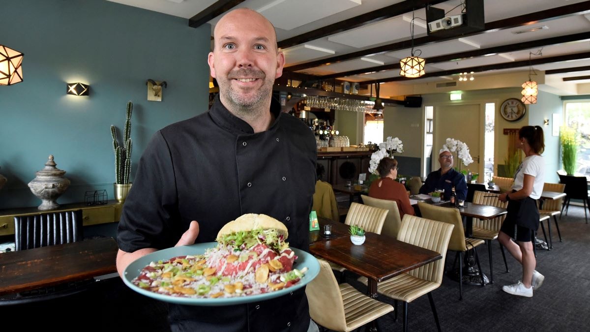 Michel Wouters laat een gerecht zien in het door hem opgeknapte interieur van brasserie De Halve Maan. Foto: Rianne den Balvert