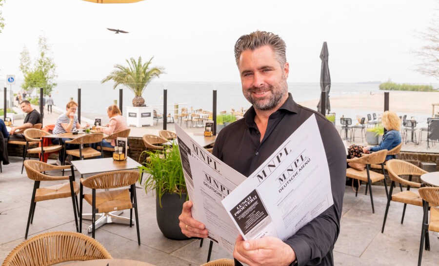 Arjan Visch, eigenaar van hotel-restaurant Monopole in Harderwijk, met een Duitse menukaart. Foto: Ruben Schipper Fotografie