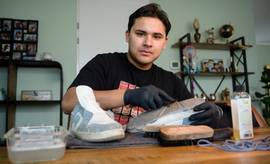 Joey van den Bergh van Happy Sneakers is bezig met het schoonmaken van sneakers. Foto: Cees Elzenga