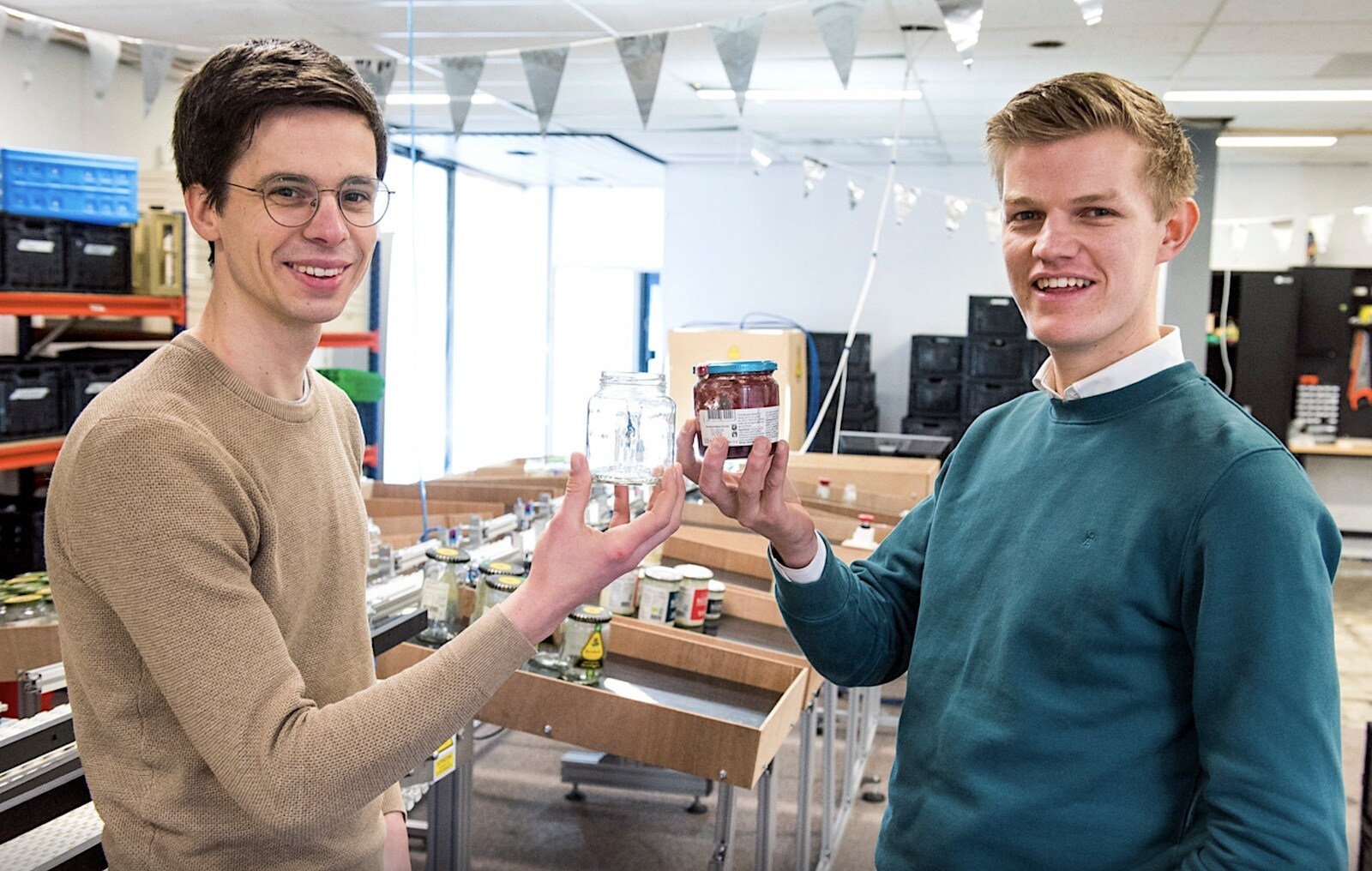 Peter Verweij en Thijs Wester met in hun handen een schoongemaakt glazen potje en een potje dat nog vies is. Foto: Marnix Schmidt