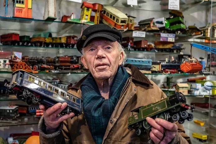 Jacob Wieringa laat twee modeltreinen zien uit zijn stampvolle winkel. ,,Het is een stuk idealisme en ik ontmoet allemaal aardige mensen.” Foto: Ronald Hissink
