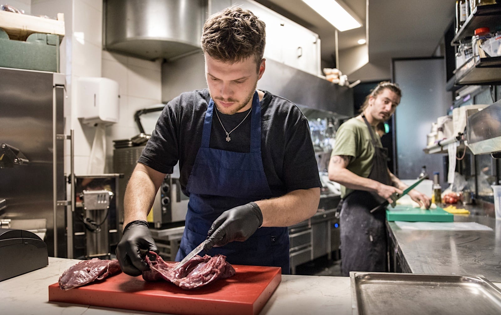 Kok Rokus de Jong snijdt het vlees in DiepNoord. Hij opende het restaurant anderhalve maand geleden samen met Sam Hoffstaetter. Foto: Arie Kievit