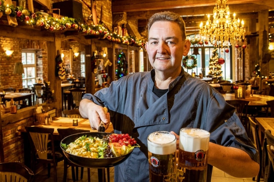 Eigenaar Wijnandus Meppelink van Beim Schweinswirt met twee grote glazen bier en käsespatzle, een van de vele gerechten van het typisch Zuid-Duits restaurant pal over de grens bij Hezingen. Foto: Vincent Jannink