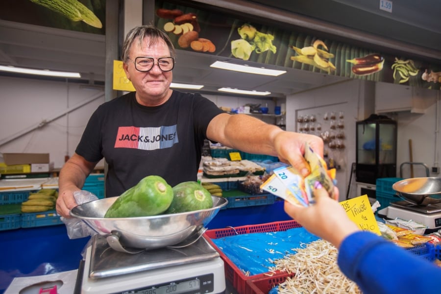 De Haagse marktkoopman Cees Becker rekent af met een klant. Zijn bank is verbaasd over de grote hoeveelheid contant geld die hij stort, maar dat is volgens hem logisch omdat het op de markt meer regel dan uitzondering is om contant te betalen. Foto: Frank Jansen