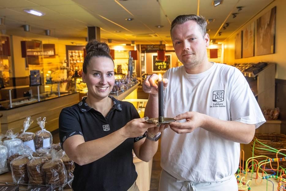 Femke Kamphuis en Wilko Wessels steken een kaars aan in hun bakkerszaak Lubbers in Almelo. Ze doen mee aan het stille protest tegen de volgens hen te beperkte energiesteun. Foto: Tubantia/Vincent Jannink.