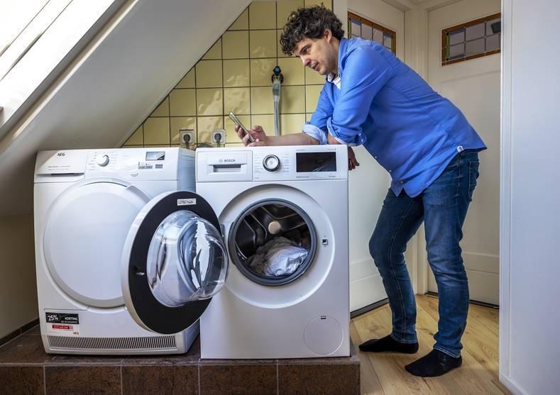 Gijs Wubbe van NextEnergy kijkt op de app en zet de wasmachine en droger aan wanneer de energie het goedkoopste is. Foto: Angeliek de Jonge