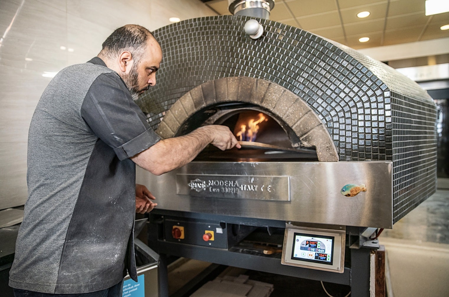 Bakker Omar van bakkerij Alsady uit Assen bakt Turkse pizza’s in een gasgestookte oven. Beeld Harry Cock/de Volkskrant