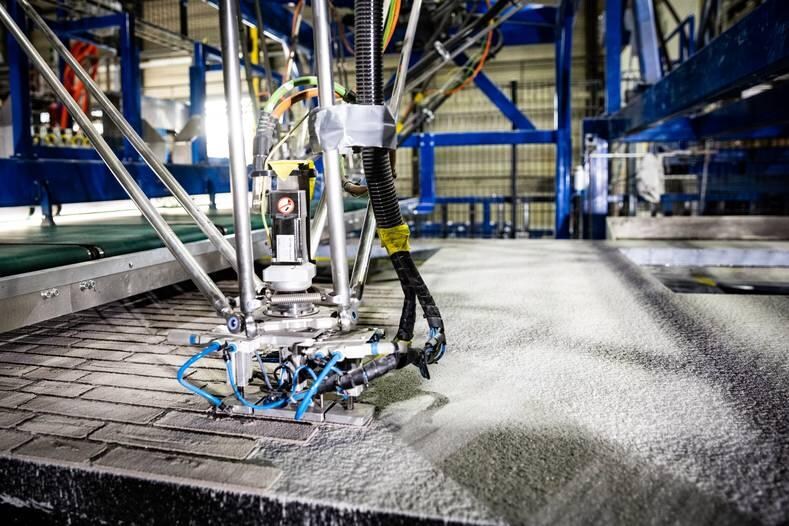 Een metselrobot legt bij RC Panels in Lemelerveld 1400 stenen in 12 minuten. De gevels kan hij helemaal compleet afleveren: met steenstrips in alle soorten, vormen, kleuren en maten, ramen, stopcontacten, leidingwerk, warmteterugwininstallaties en ventilatiesystemen. Foto: RC Panels