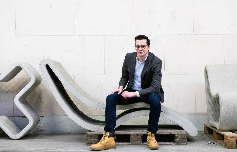 Marijn Bruurs, adviseur digital constructions bij ingenieursbureau Witteveen+Bos in Deventer zit op een geprint meubel. ,,We hebben ook 3D-betongeprinte picknicktafels. Alleen met de perfecte zithouding voor mij, haha, ik was het pasmodel." Foto: Beeld Houdbaar - Viorica Cernica