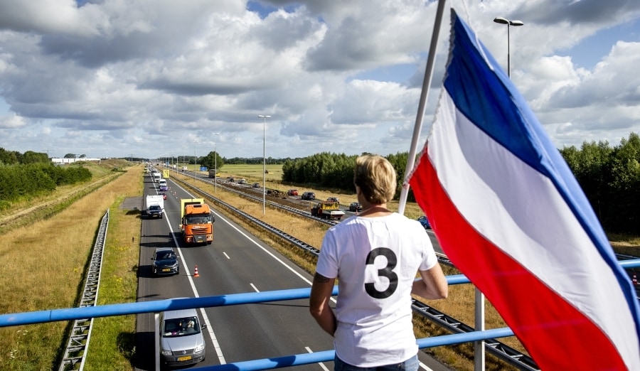 Een sympathisant kijkt met omgekeerde vlag toe naar de file op de A50, nadat boeren mest en ander puin hebben gedumpt. Foto: ANP.