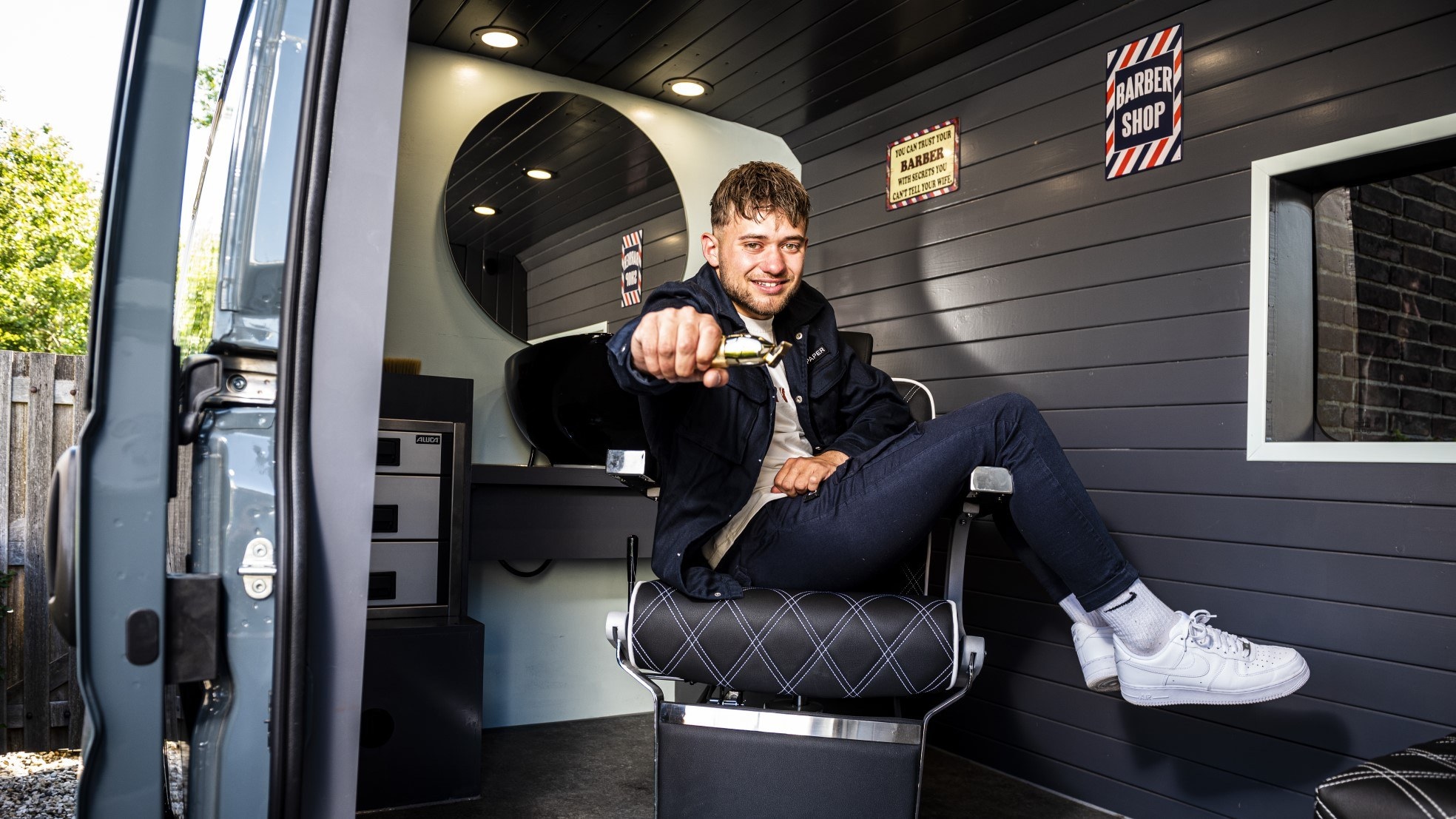 Barbier op wielen Dani Brussen neemt buurman Mark even onder handen in zijn nieuwe rijdende kapsalon. Foto: Merel Klijzing