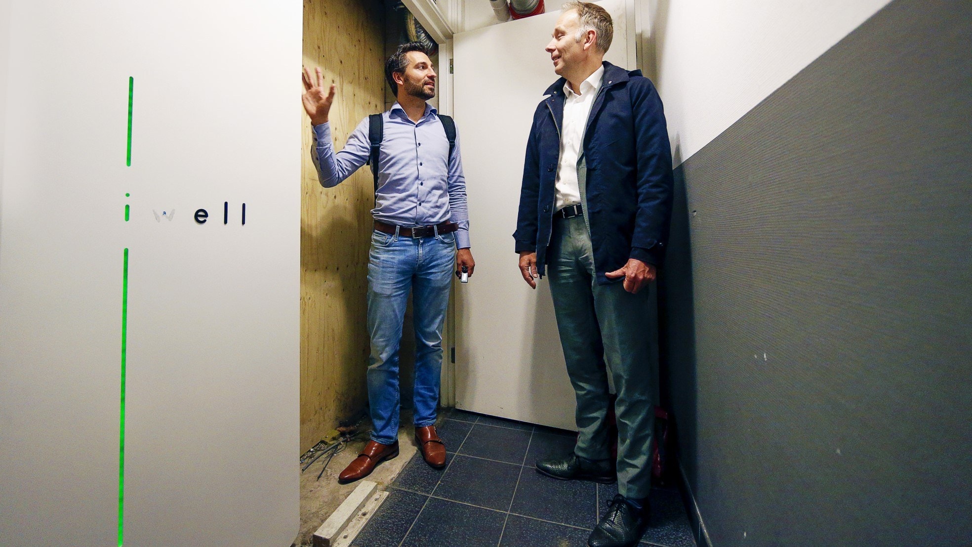 Twee grote batterijen (links in beeld) bieden uitkomst aan het Rolderdiephof in de Dichterswijk. Vincent Ruijter van leverancier iWell praat gedeputeerde Huib van Essen (rechts) bij over de mogelijkheden. Foto: AD/Ruud Voest.