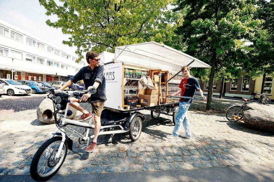 Medeoprichter Laurens Kok (op de fiets) en Job Krijger bij de verpakkingsvrije mobiele supermarkt Loos. Foto: AD/Ruud Voest.