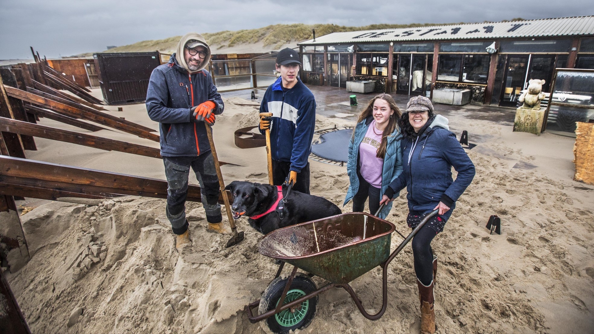 Moussa, Midas, Kayleigh en Patricia zijn keihard bezig om de muur op te bouwen die strandpaviljoen De Staat moet beschermen tegen de nieuwe storm die komt aanrazen. Foto: Frank Jansen