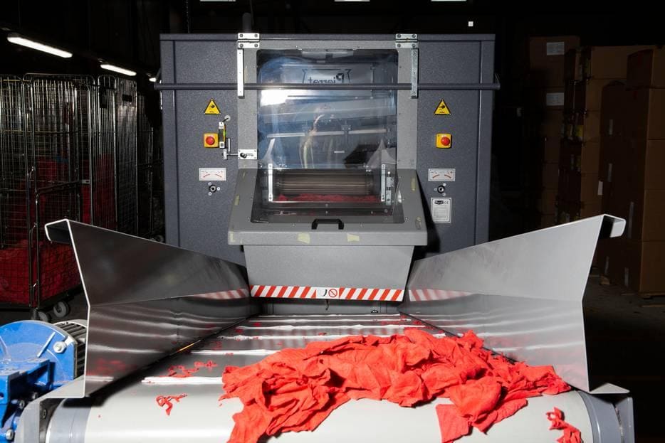 De nieuwe machine uit Wormerveer die de uitgesorteerde kleding aan flarden snijdt en van ritsen, knopen en stiksels ontdoet. Foto: Het Parool/Daphne Lucker.