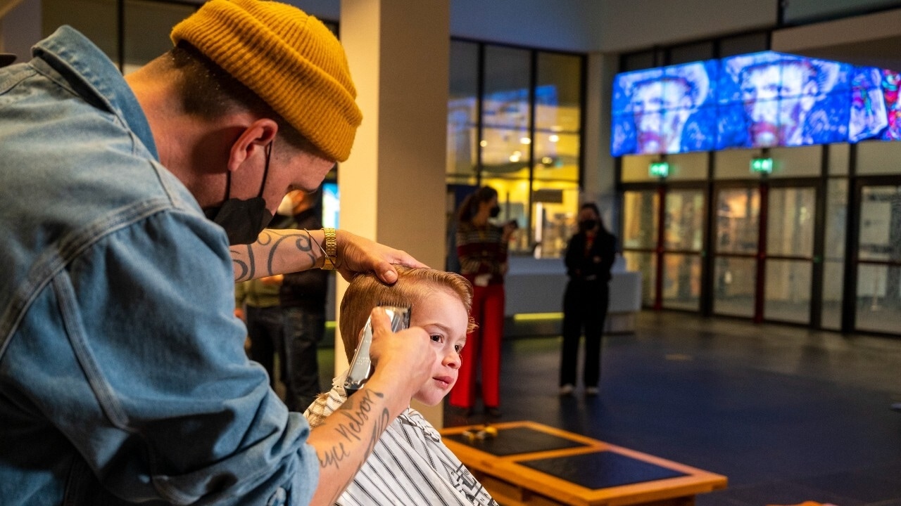 Een barbier knipt het haar van een piepjonge bezoeker in het Van Gogh Museum. Foto: ANP
