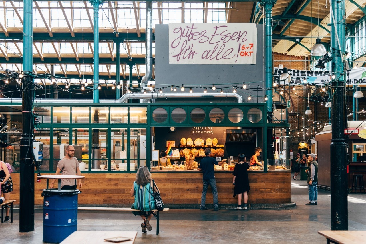 Rondom de Markthalle Neun (foto) een overdekte markt met kraampjes vol eten en spulletjes, blijven veel rolluiken van dicht. Sommige winkeliers hebben de moeite genomen een briefje op te hangen. ‘Beste klanten, helaas ben ik vandaag en morgen niet in de winkel.’ Andere zaken hebben besloten om bijna heel januari dicht te blijven zoals een feestartikelenwinkel, waarvan de etalage vol met kerstspullen een treurige aanblik geeft.