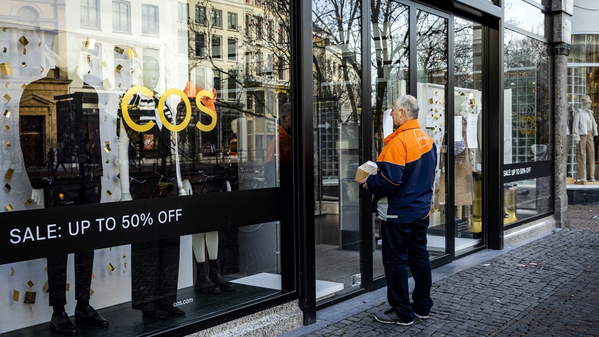 Een pakketbezorger wacht voor een dichte winkel in het centrum van Utrecht. Foto: ANP
