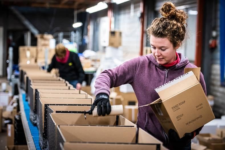 Tamara pakt kerstpakketten in. Er is een groot tekort aan karton en papier, daarom is er maar zeer beperkt keuze uit het soort dozen. Foto: Merel Klijzing