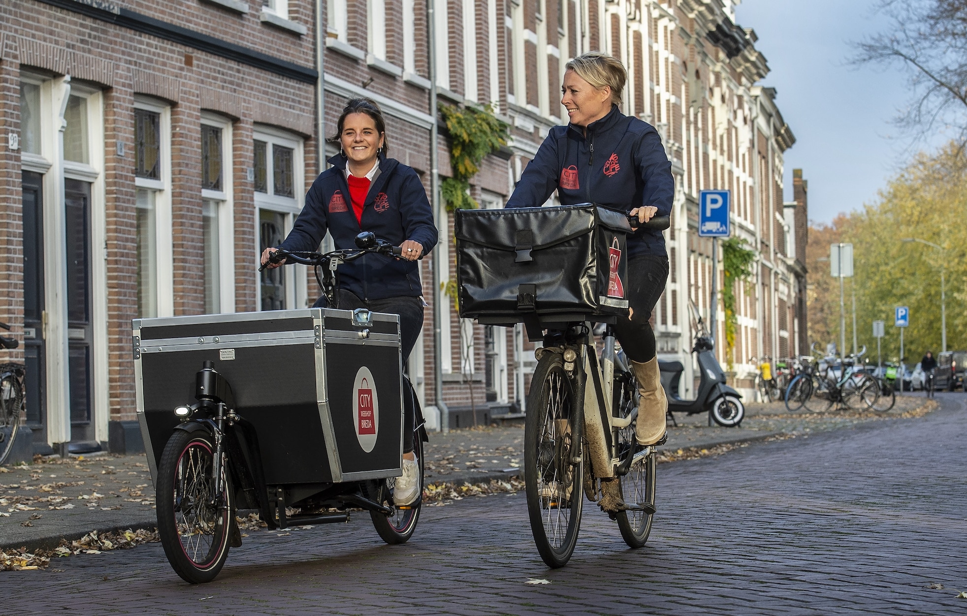 Juul Hoekstra (l) en Merel van Gijzel-Mens zijn de gezichten achter City Webshop Breda. Ze runnen de webshop voor tachtig kleine, lokale winkeliers en regelen de bezorging van alle producten. Foto: Pix4Profs-Ron Magielse