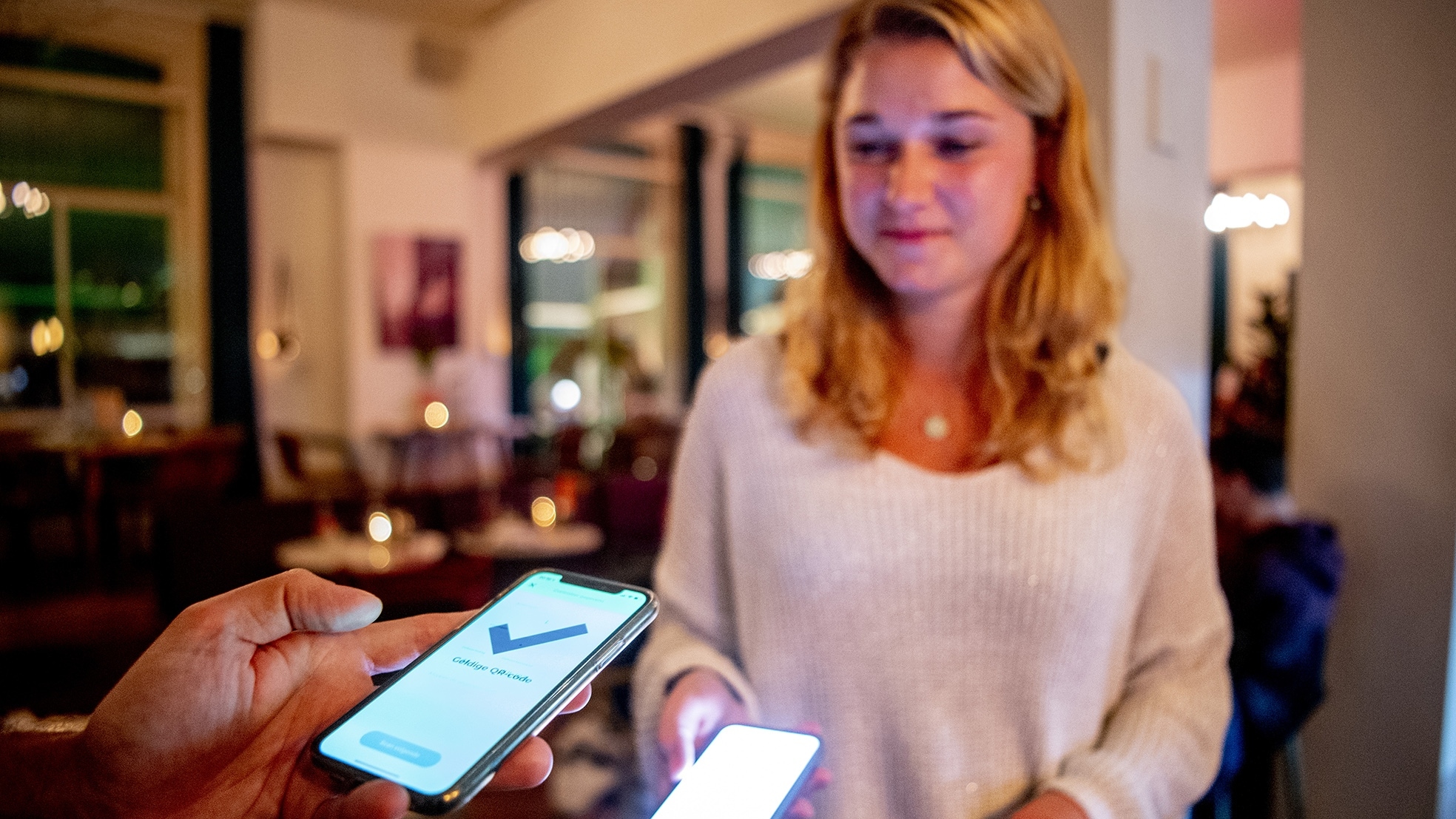 Bezoekers van een cafe laten voor binnenkomst hun QR-code scannen. Het OMT liet weten dat de coronamaatregelen beter moeten worden uitgevoerd en dat de regels in de horeca beter moeten worden nageleefd. Persoon komt niet in het verhaal terug. Bron: ANP Foto.
