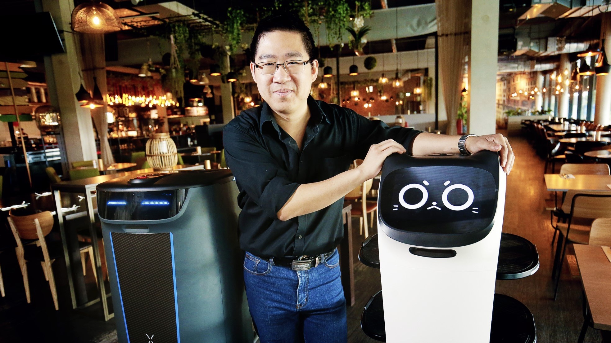 Eigenaar Deon Poon met zijn robots die de bediening in het restaurant over kunnen nemen. Foto: Ruud Voest