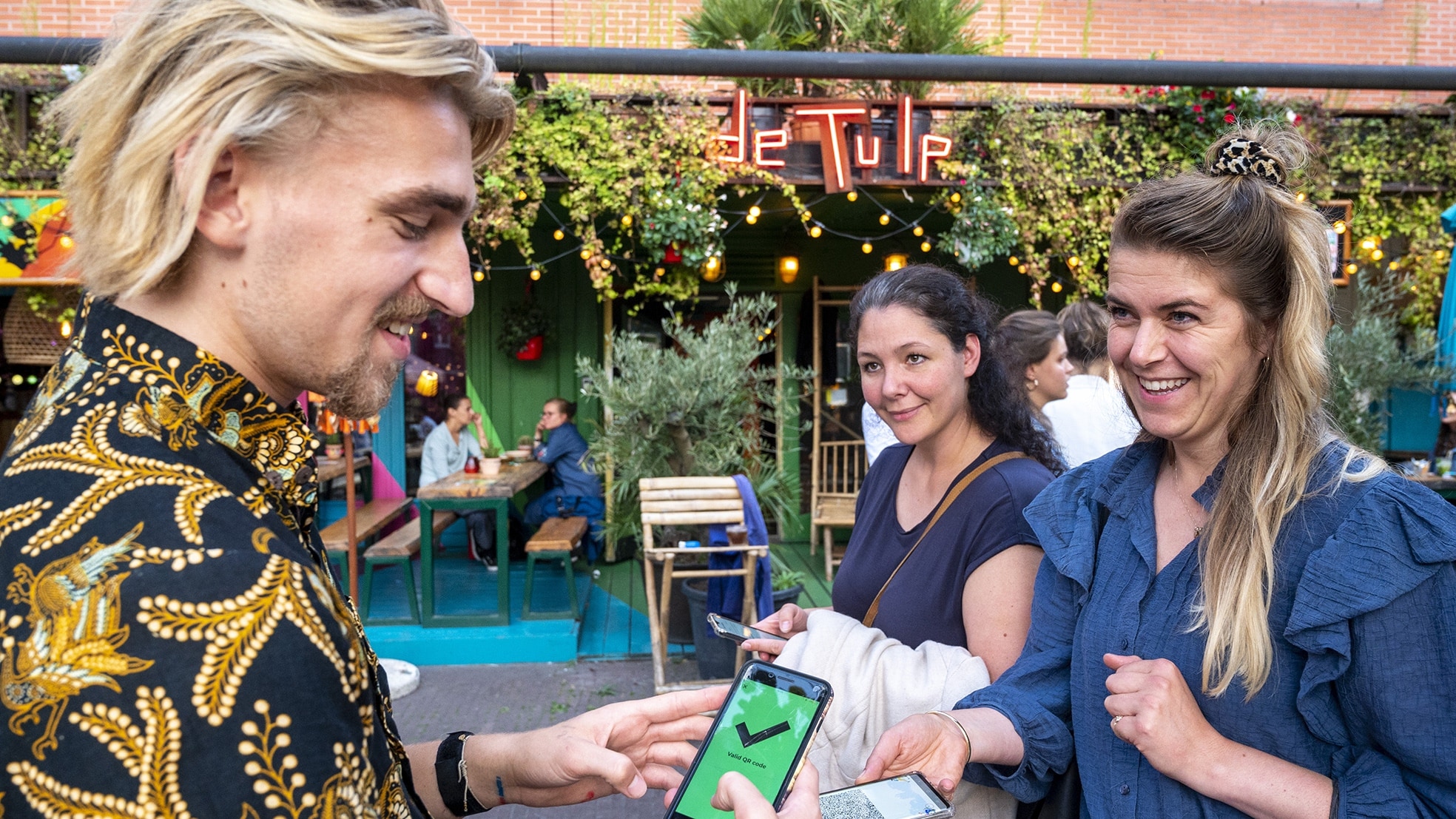 Een QR-code wordt gecontroleerd voor toegang tot een café. Bron: ANP Foto
