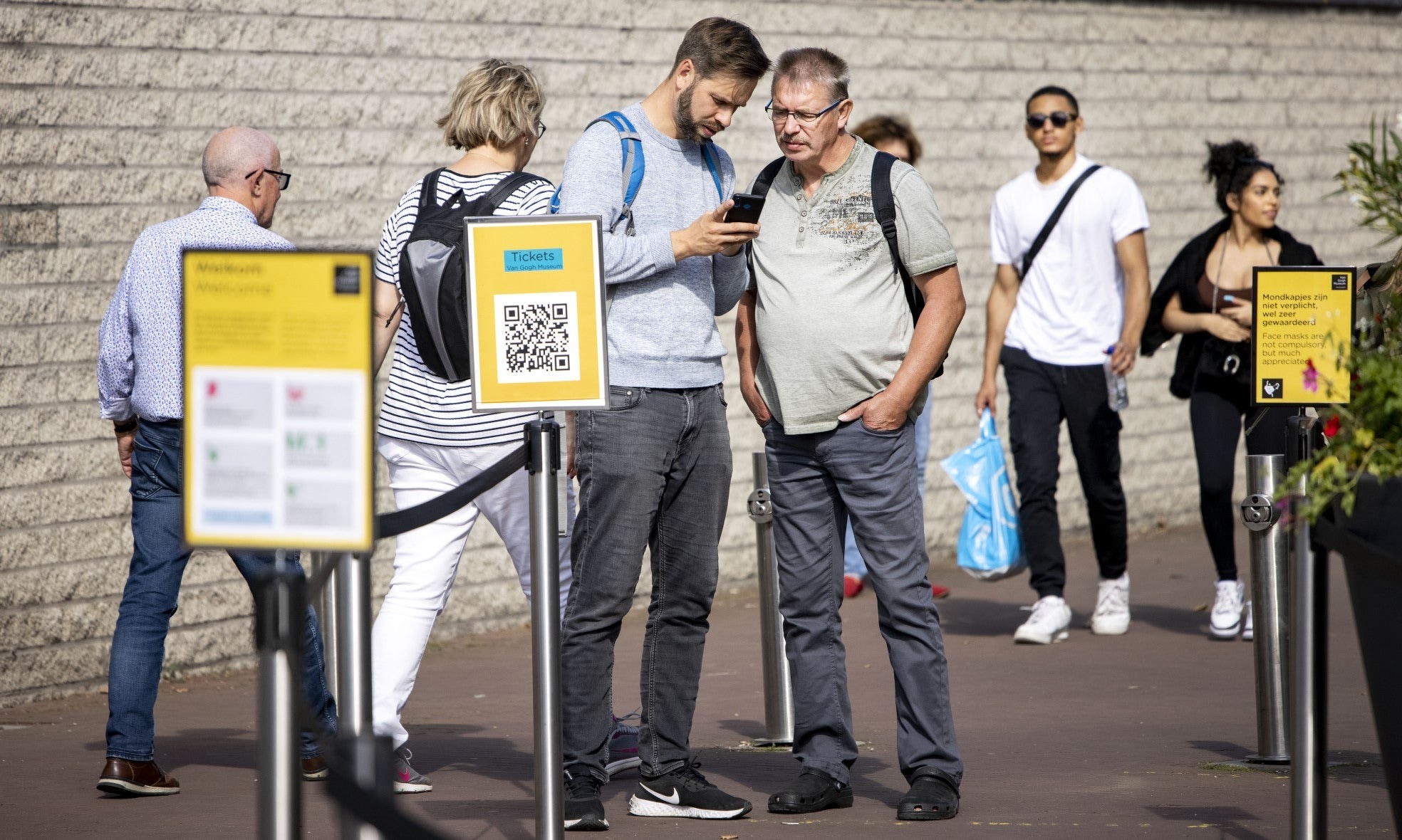 Bezoekers bij de ingang van het Van Gogh Museum met hun mobiele telefoons. Het kabinet wil een coronapas voor toegang tot horeca en culturele instellingen. Foto: ANP