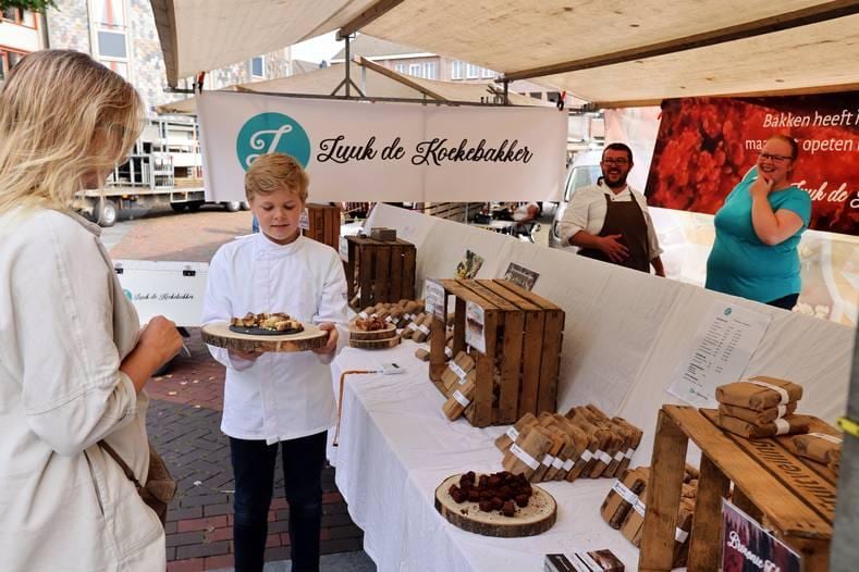 De 11-jarige Luuk de Koekebakker brengt zijn koeken aan de man op de zaterdagmarkt Spijkenisse. Foto: Peter de Jong Fotografie.