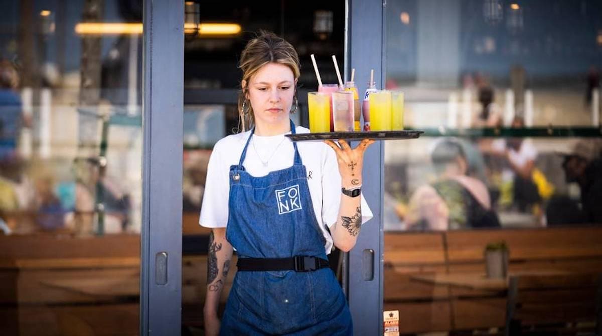 Een serveerster aan het werk in Scheveningen. Door de coronacris is er groot tekort aan horecapersoneel, omdat een deel inmiddels ander werk heeft gevonden. Foto: Freek van den Bergh