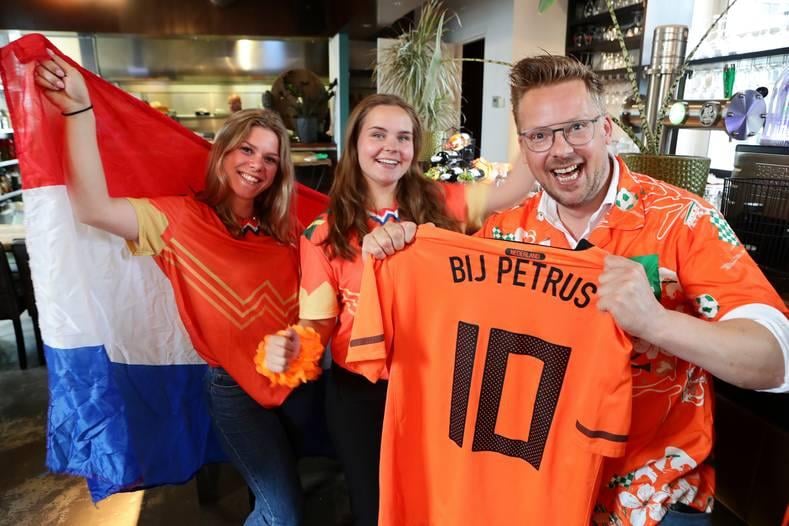 De serveersters Evi en Katja en eigenaar Martijn Gerits van Bij Petrus zijn helemaal klaar voor de wedstrijd van Oranje zondag tegen Tsjechië. Foto: AD/Ricardo Smit.
