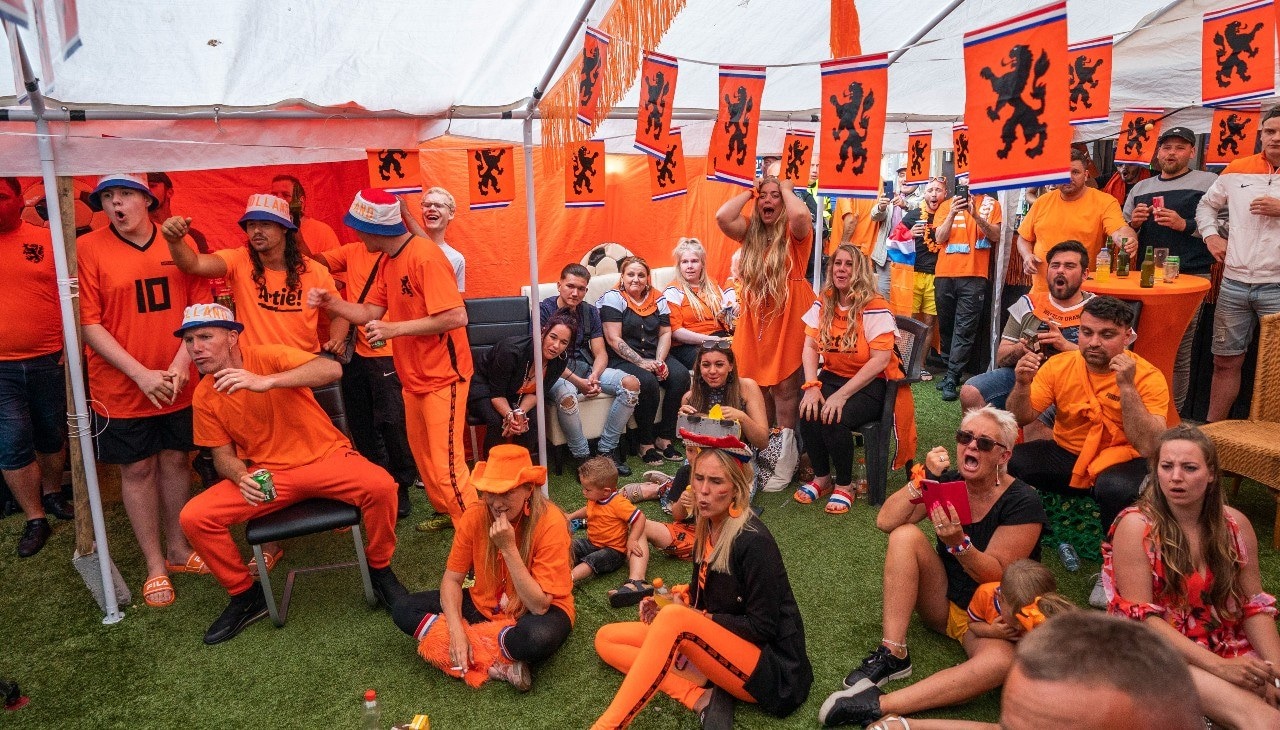 Bewoners van de Marktweg in Den Haag kijken gezamenlijk vanuit hun achtertuin naar de EK-voetbalwedstrijd Nederland-Oekraïne. Foto: ANP.