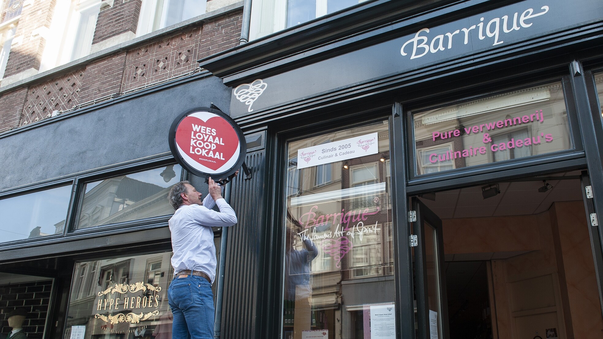 Een ondernemer in Den Bosch hangt een bord op 'Wees loyaal, koop lokaal'. Om het belang van steun voor de eigen ondernemers weer te geven om zo een dubbele economische dip te voorkomen. Foto: Olaf Smit.