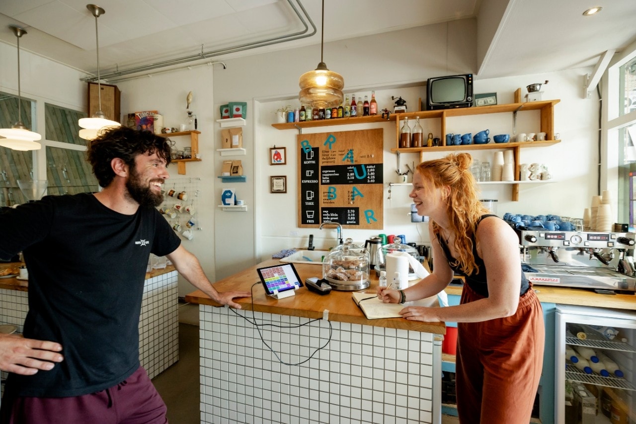 Een klant van Koffie Leute Brauhaus in Utrecht vult haar contact gegevens in bij aankomst in de koffiefilterbar. Bezoekers van horecagelegenheden moeten bij aankomst hun naam en contactgegevens laten registreren, zodat die gebruikt kunnen worden voor bron- en contactonderzoek om het coronavirus in te dammen. Foto: ANP.