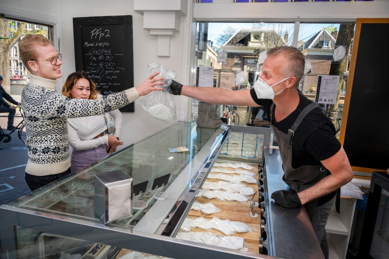 In winkelgebieden in Amsterdam en Rotterdam gaat het verplicht worden: mondkapjes dragen. Er zijn al winkeliers die dat inmiddels zelf doen (zie foto) en als het aan consumentenpsycholoog Patrick Wessels ligt, zouden alle winkeliers dat voorbeeld moeten volgen. Foto: ANP.