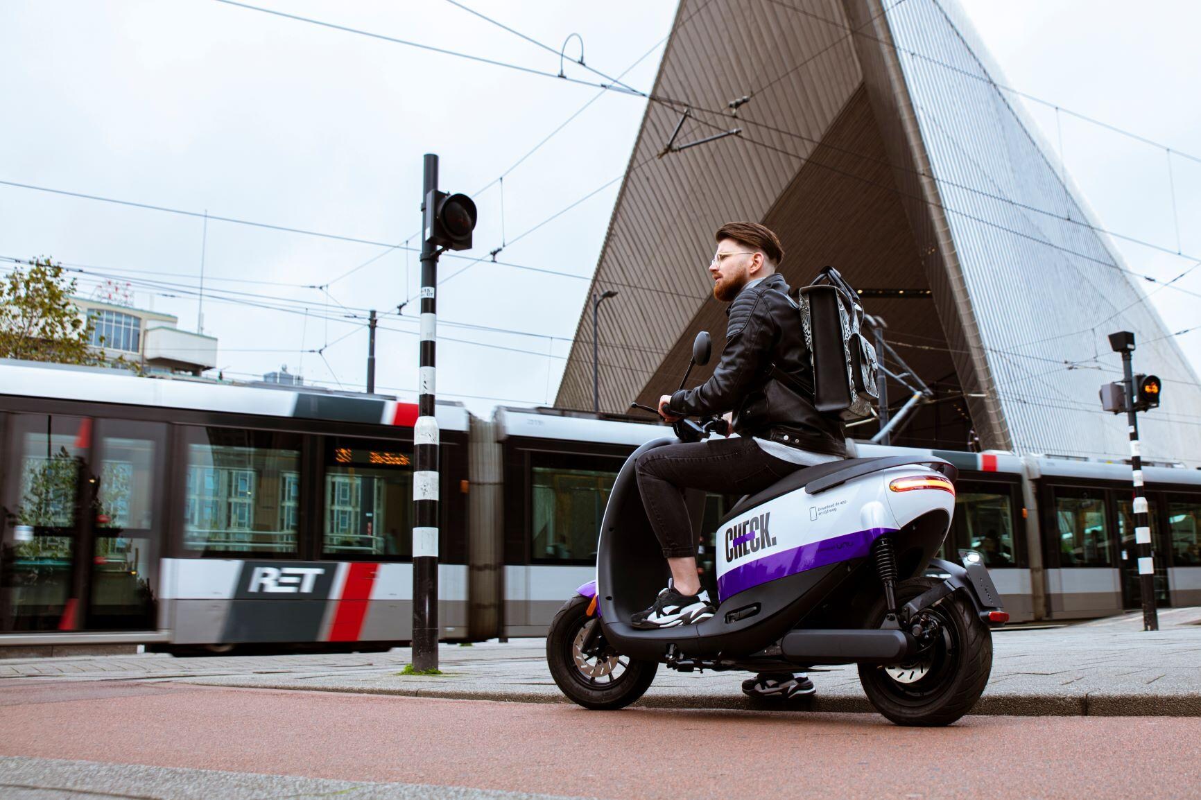Een deelscooter van Check. Onder: de oprichters van Check. Zittend Marco Knitel, staand Paul van Merrienboer. Foto's Check