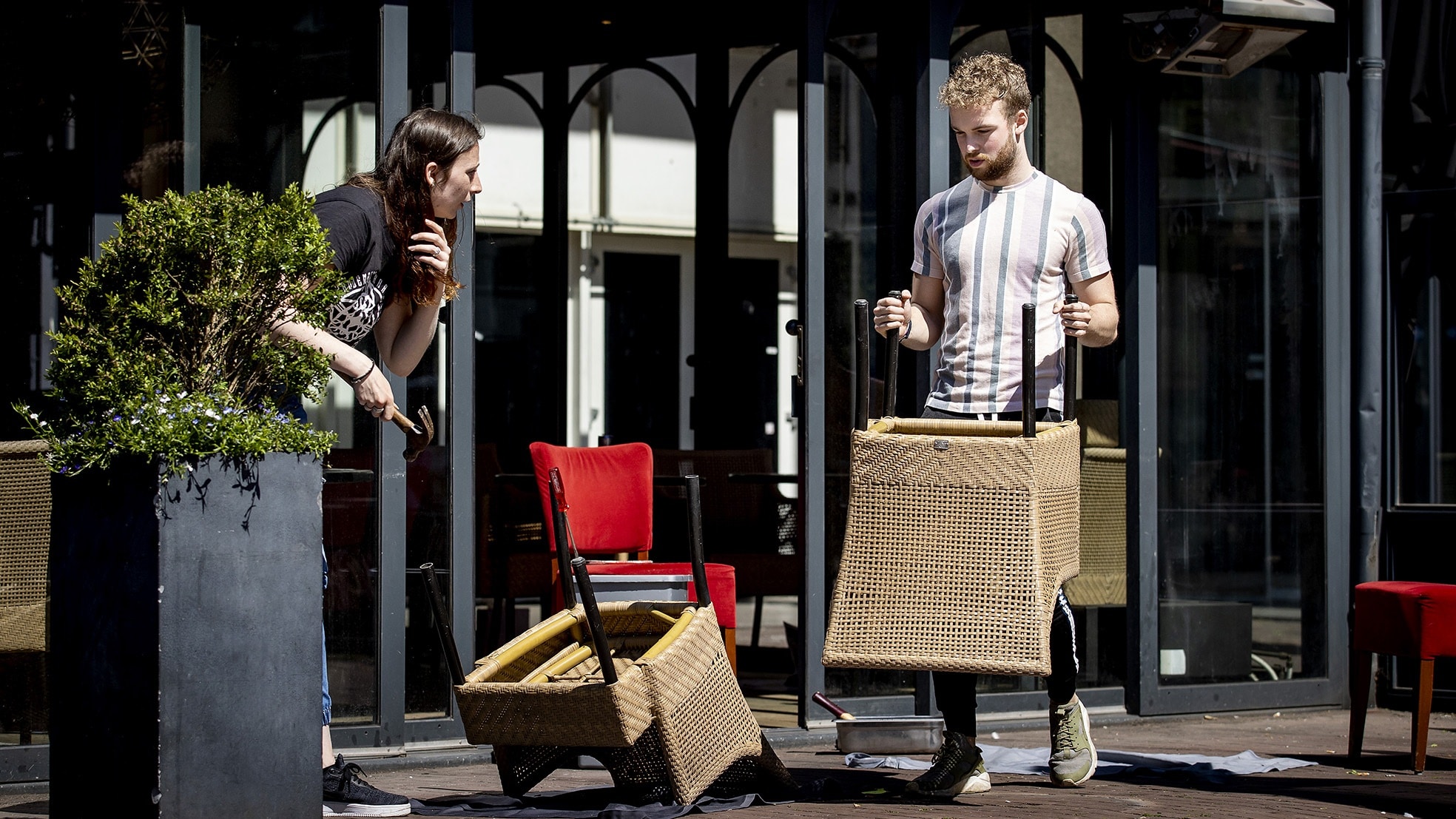 Medewerkers van een horecazaak in Amsterdam knappen buiten de terrasstoelen alvast op voor 1 juni. Foto: ANP