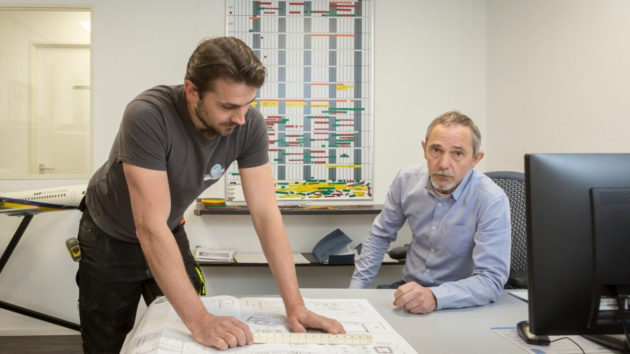 Ed (rechts) en Guus Luthart voor het leeg geveegde planbord (foto hierboven) en uitkijkend over de verlaten hal waar normaal gesproken stands worden voorbereid (foto onder).Foto's: Machtelt Mostert.