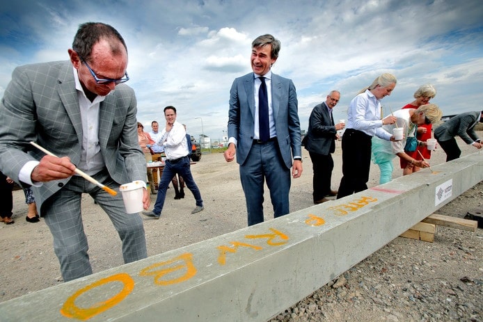 Rientz Willem Bol (rechts) kijkt in betere tijden toe hoe zijn naam, net als die van zijn medewerkers op een heipaal gezet wordt. 'De medewerkers zijn het fundament van dit bedrijf'