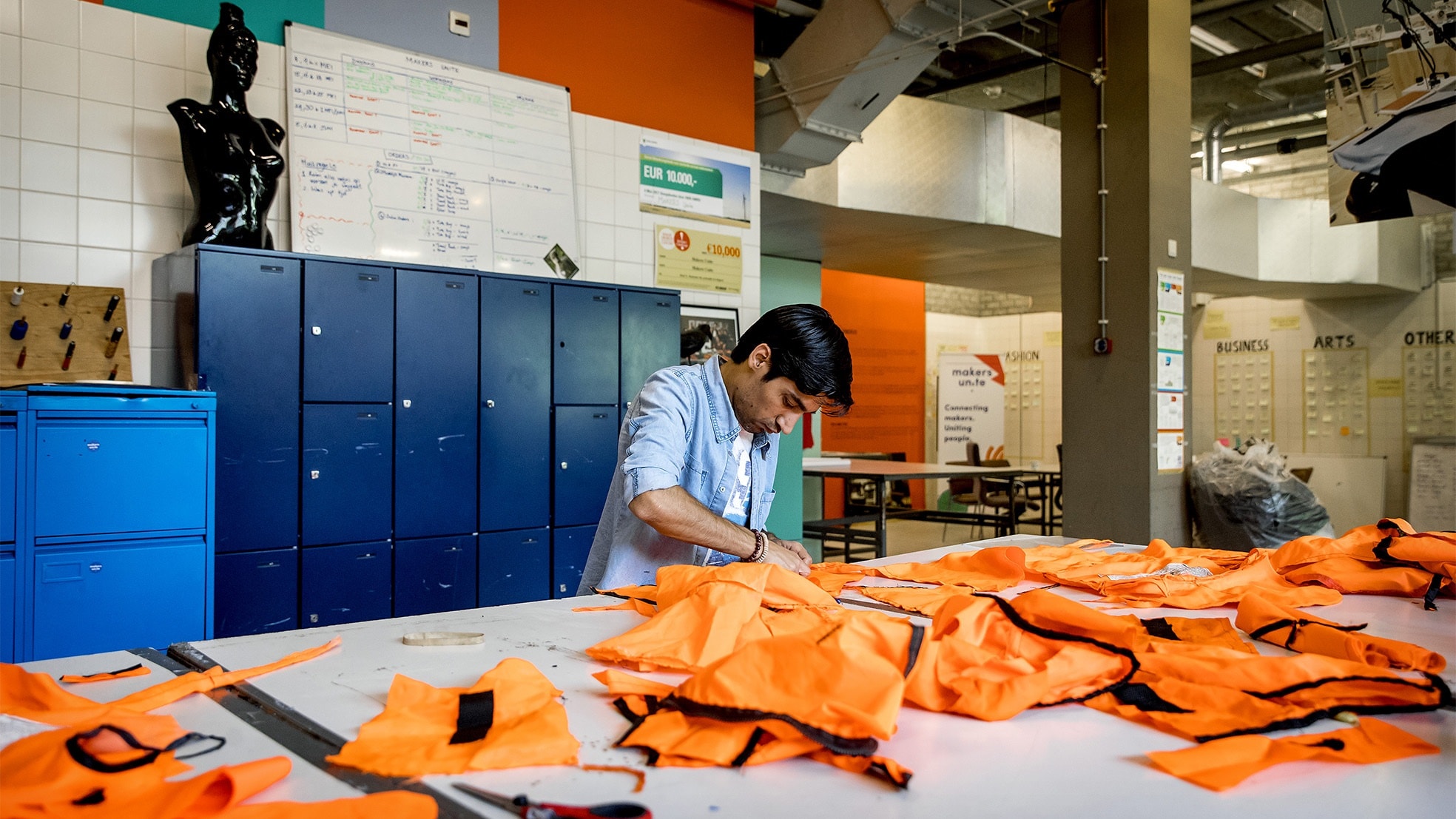 Medewerkers van Makers Unite maken tassen uit zwemvesten die vluchtelingen gedragen. De organisatie is een sociale onderneming die lokale Amsterdammers en nieuwkomers bijeen brengt om samen betekenisvolle en duurzame producten te maken. (Foto: Koen van Weel/ANP)