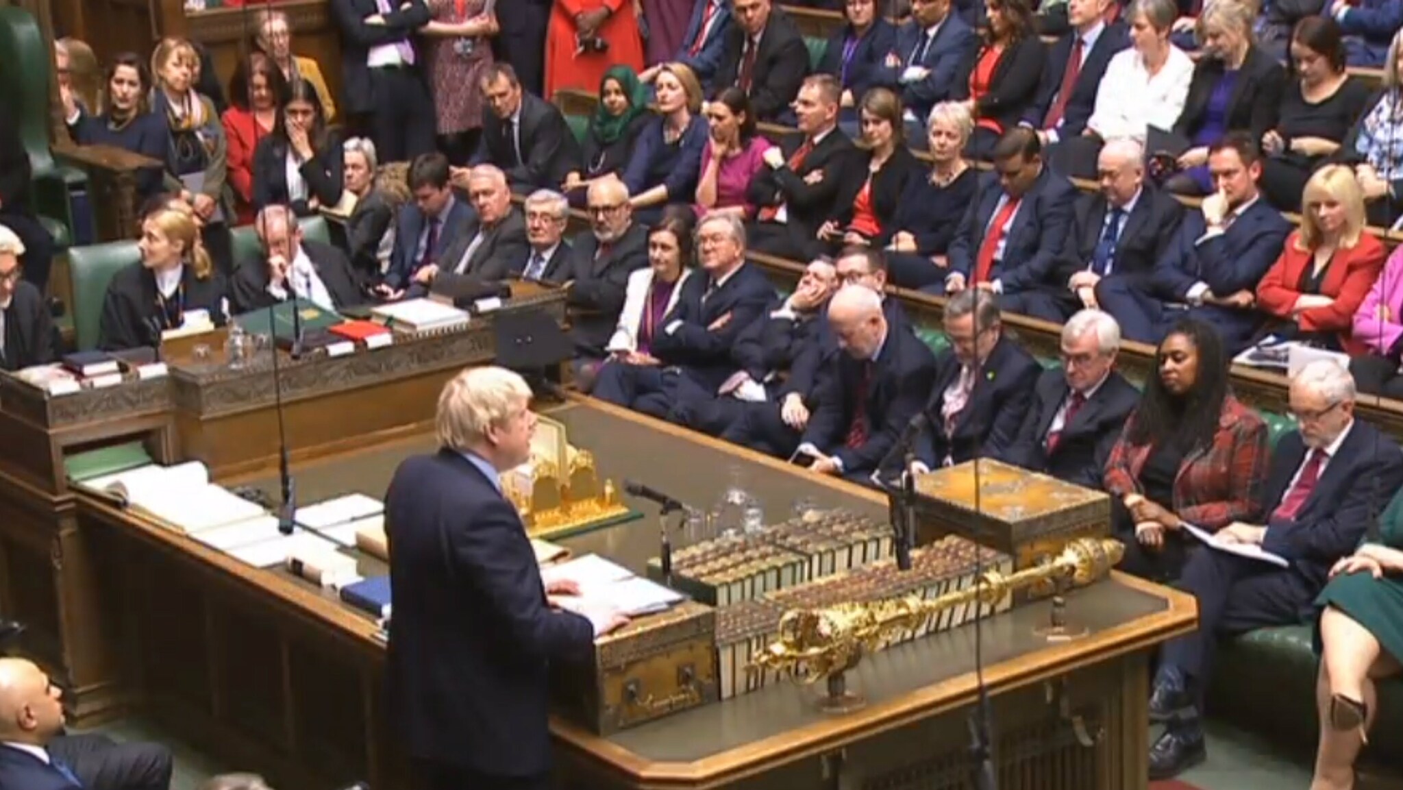 Boris Johnson in 'zijn' Lagerhuis, na de verkiezingszege. Johnson oreert, Corbyn (rechts) kent zijn nieuwe plek.
