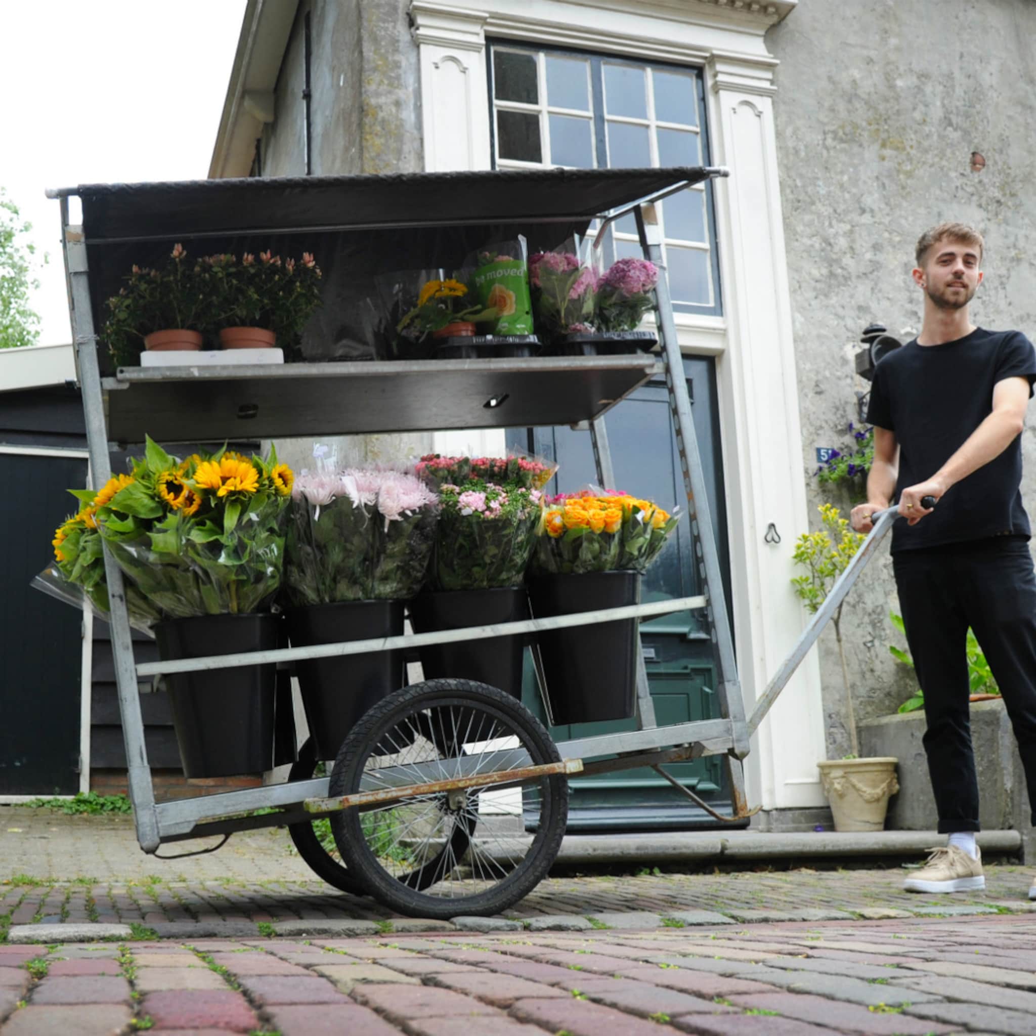 student met eigen bloemenkar langs deuren in veere
