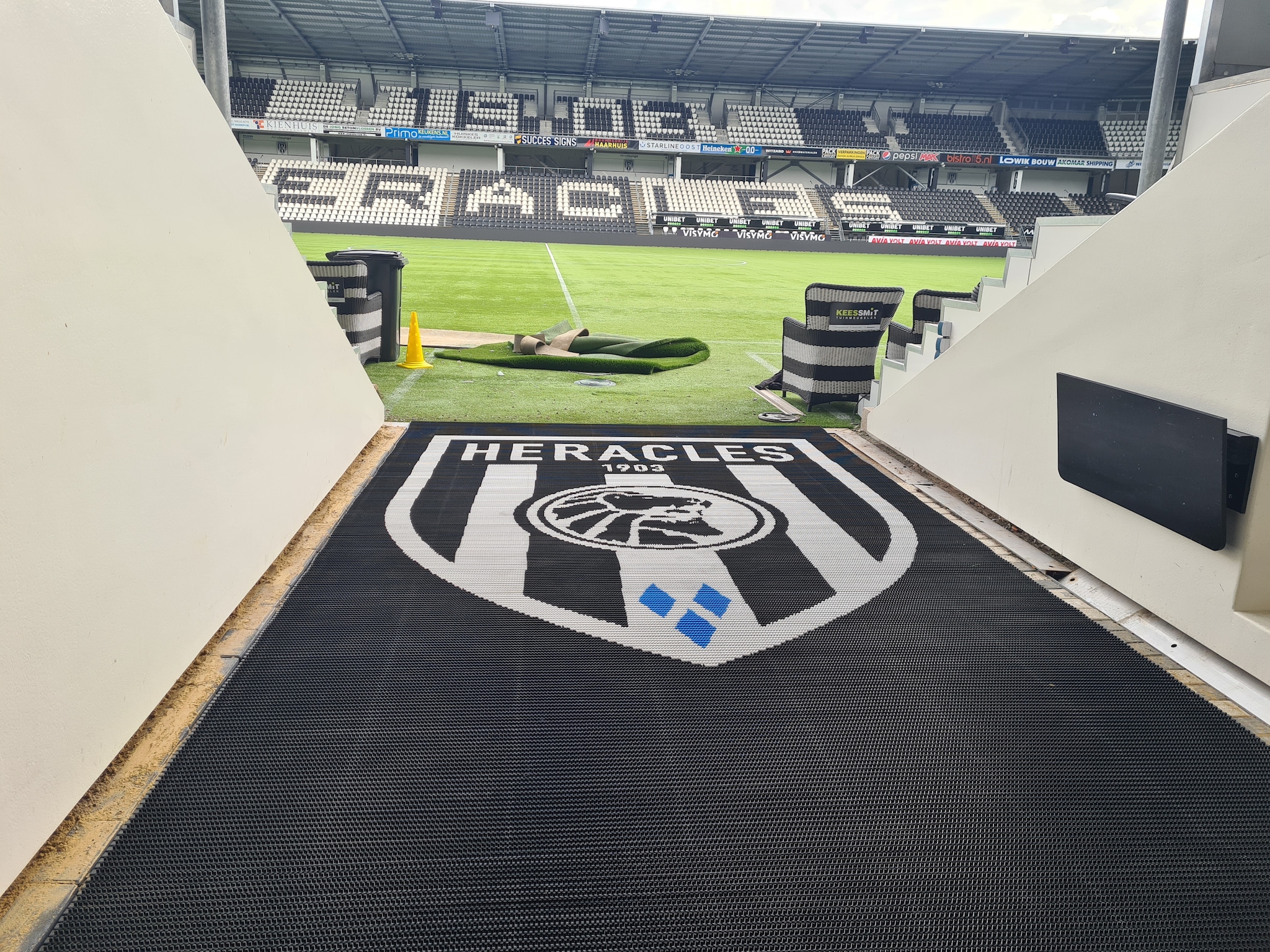 De borstelmat met het clubembleem van Heracles in de spelerstunnel van Erve Asito is ook een product van de Almelose Borstel Industrie. ABI