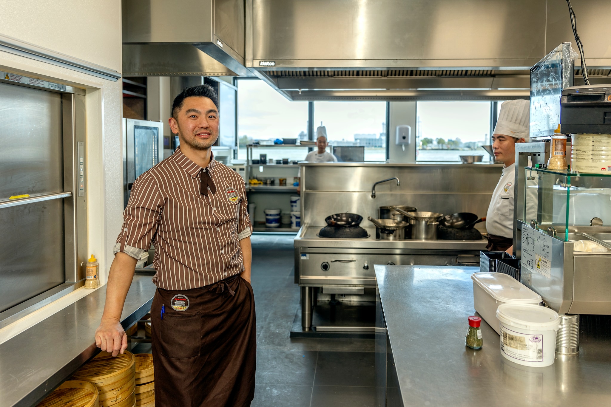 Jun Chou in de keuken van zijn zaak China Garden in Vlaardingen, rechts chef-kok Yk Zhou. Hij is niet één van de drie aangehaalde cruciale koks uit China in de keuken. Jun Chou in de keuken van zijn zaak China Garden in Vlaardingen, rechts chef-kok Yk Zhou. Hij is niet één van de drie aangehaalde cruciale koks uit China in de keuken. Foto: Dennis Wisse